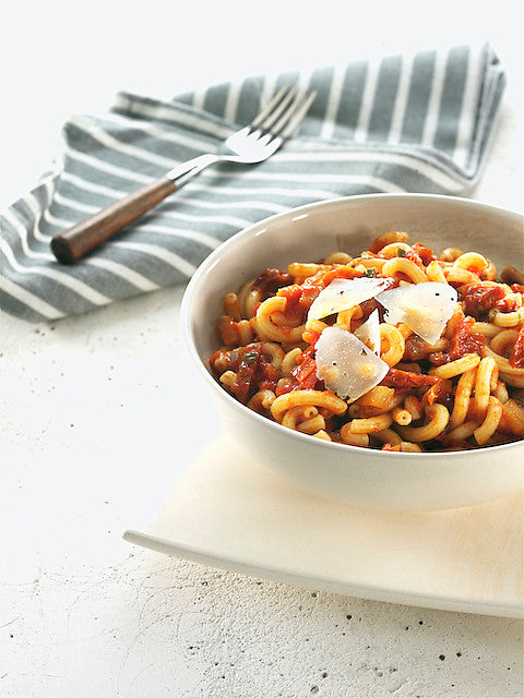 Spelt gramigna pasta with tomato sauce seasoned with aubergines and sun-dried tomatoes